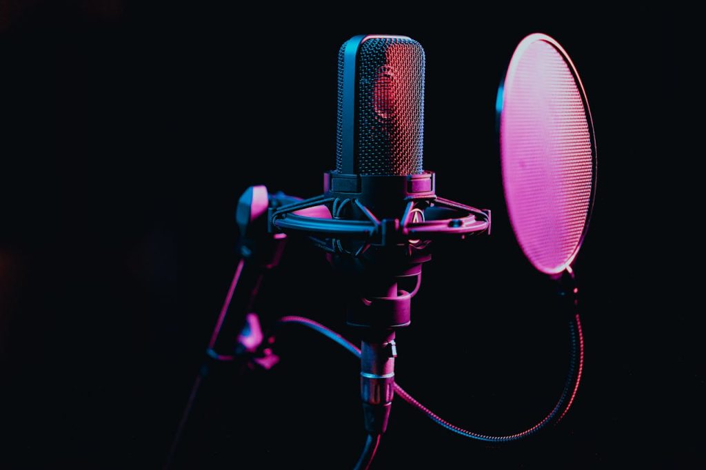 pexels photo 7586662 Close-up image of a condenser microphone with a pop filter in a studio setting, featuring atmospheric lighting.